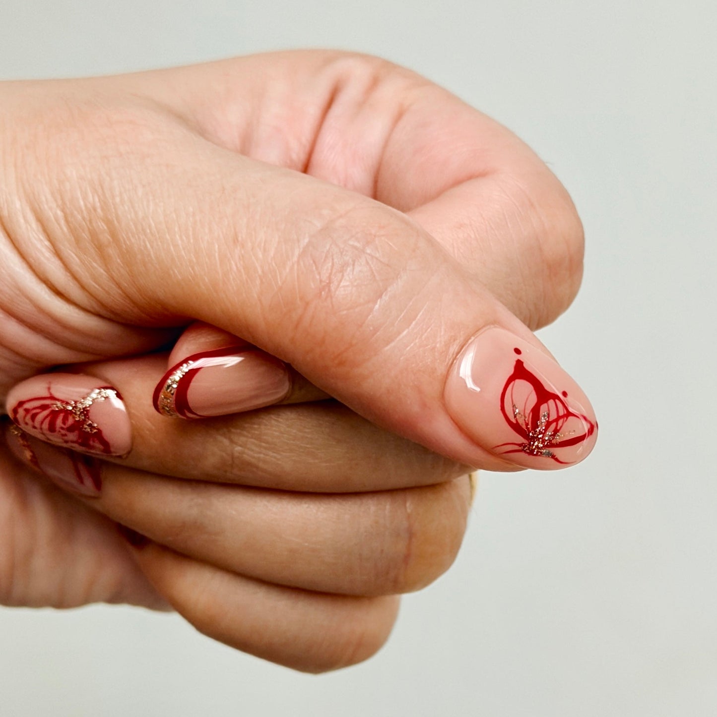 Hand with red nail art on a plain background