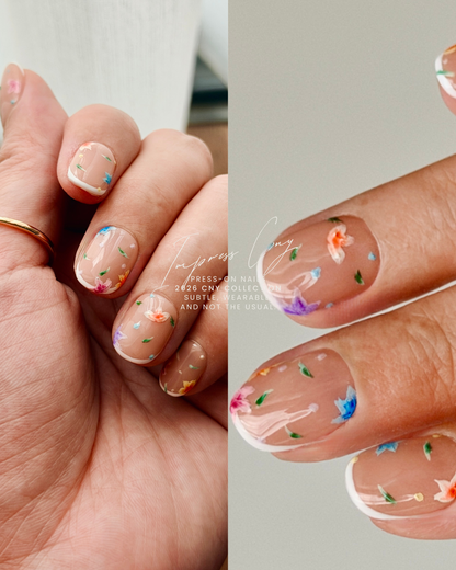 Close-up of hands with hand drawn floral press-on nails on a plain background