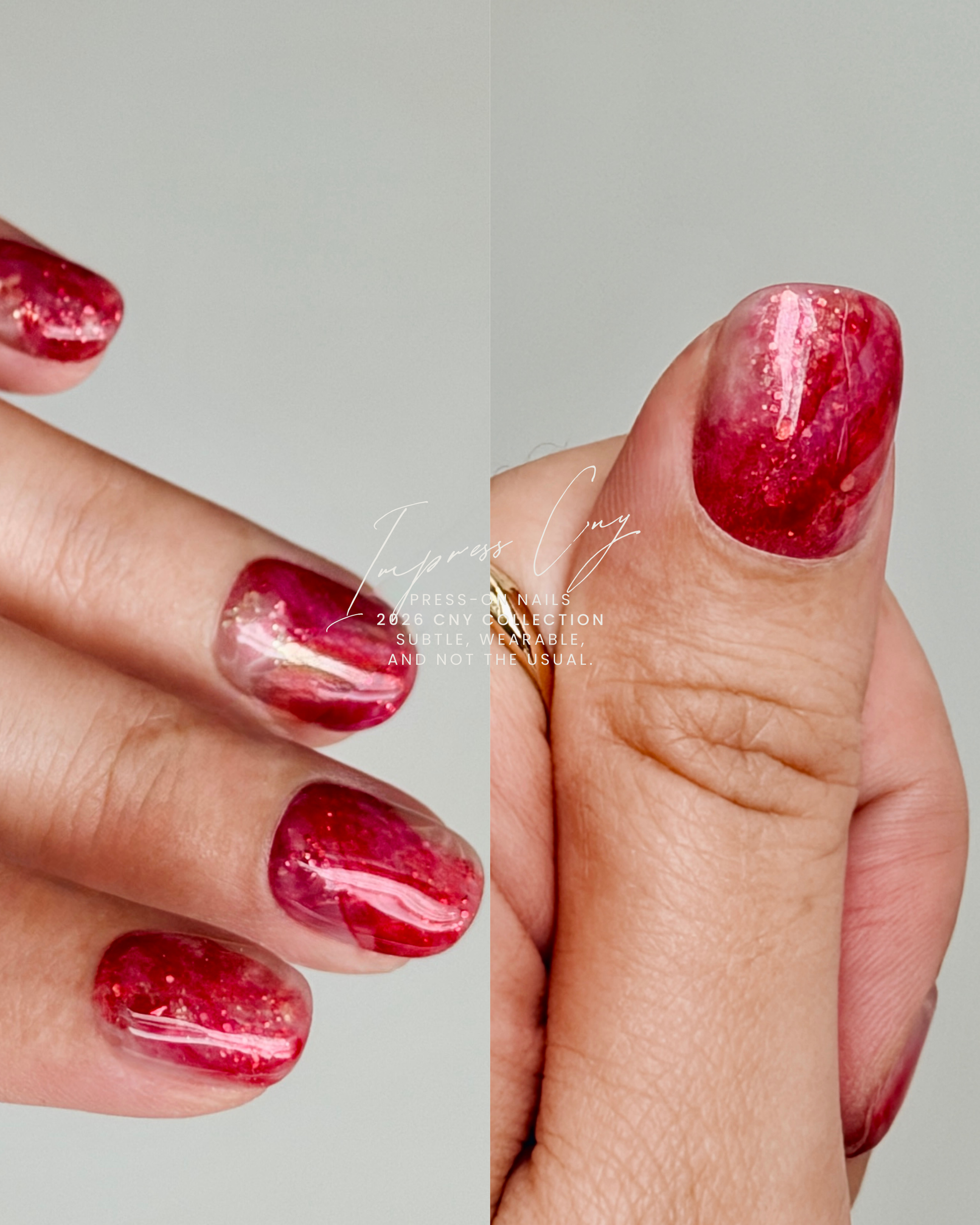 Close-up of a hand with red and gold marbled press-on nails on a neutral background