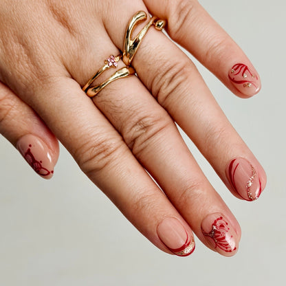 Hand with gold rings and red nail art on a neutral background