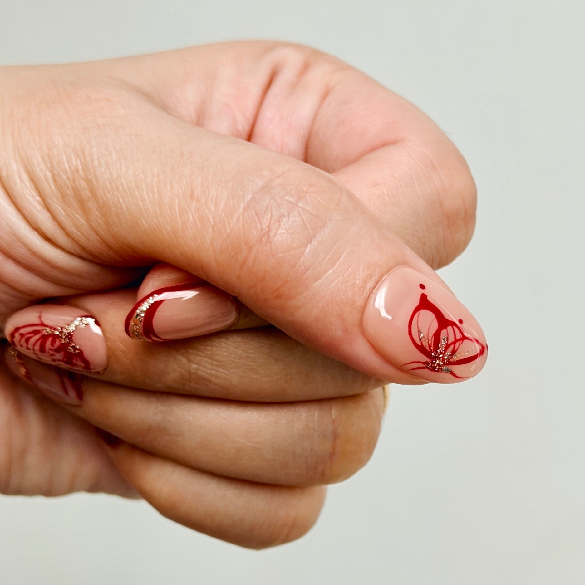 Hand with red nail art on a plain background